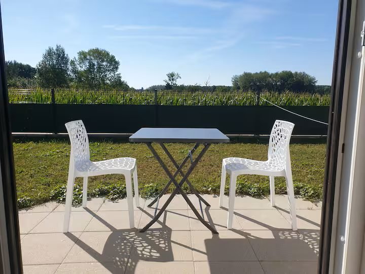 La terrasse privative du studio, sa table et ses chaises, ouverte sur les champs